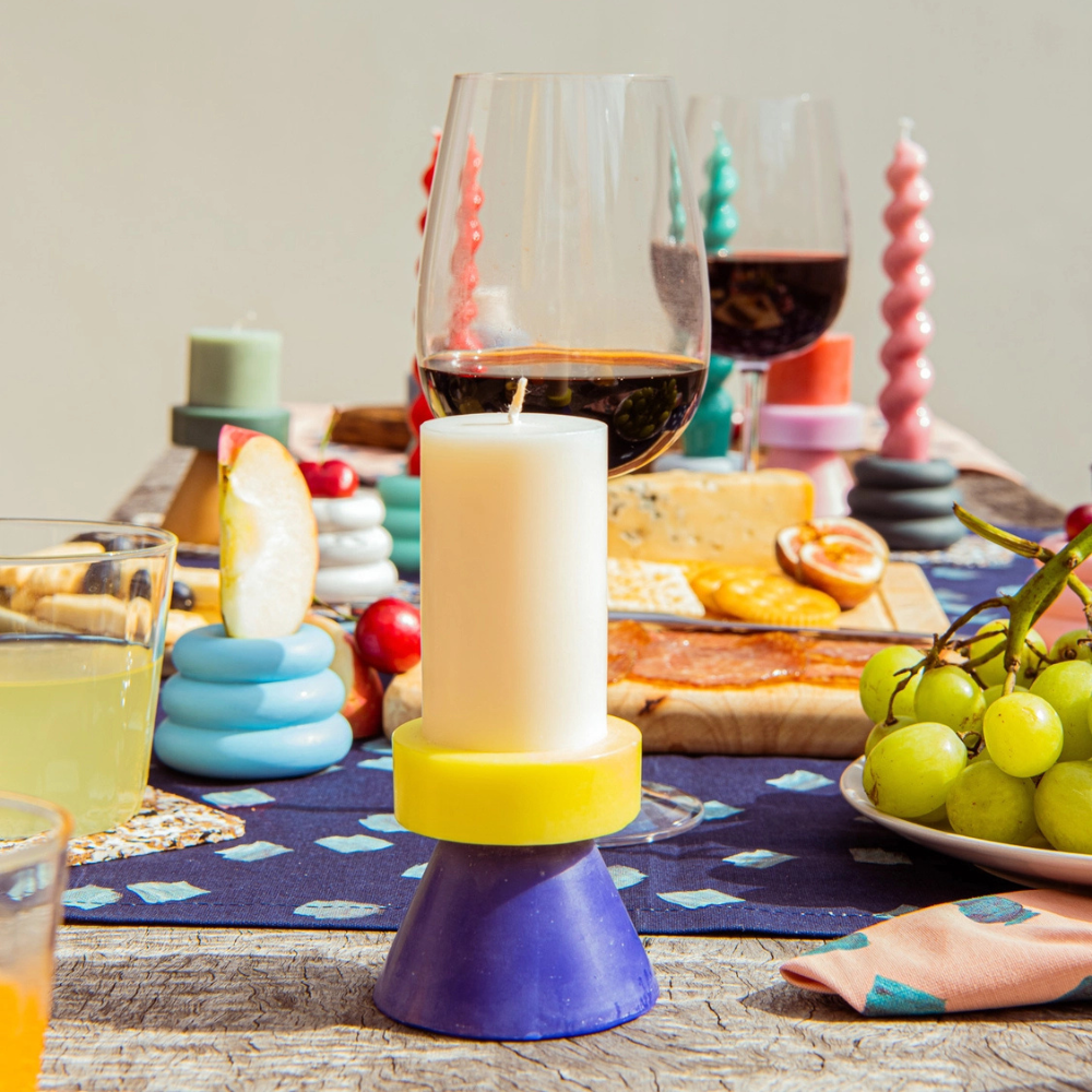 Bougie Stack Tall Yod & Co blanc, jaune et bleu sur une table dressée.