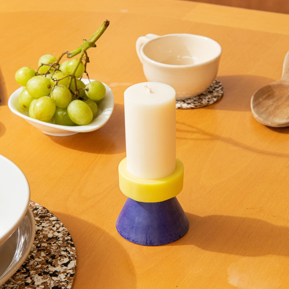 Bougie Stack Tall Yod & Co blanc, jaune et bleu sur une table orange